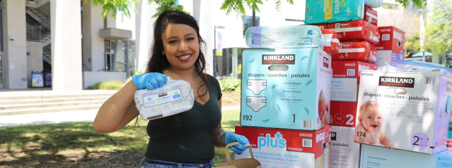 2 of 2, student handing out diapers at tabling event.